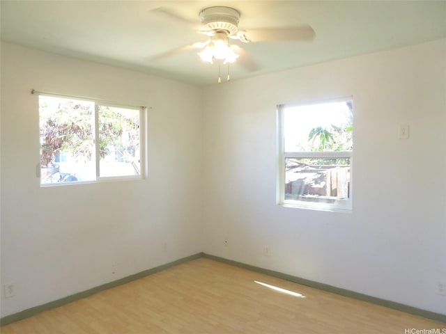 spare room featuring light wood-type flooring, baseboards, and ceiling fan