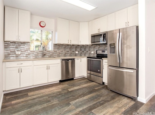 kitchen with light countertops, appliances with stainless steel finishes, dark wood-type flooring, white cabinetry, and a sink