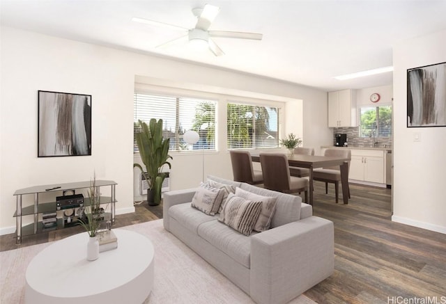 living room with dark wood-style floors, a ceiling fan, and baseboards