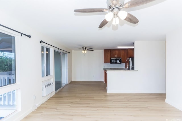unfurnished living room with a ceiling fan, baseboards, and light wood-style flooring