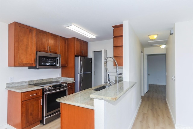 kitchen with appliances with stainless steel finishes, open shelves, light stone countertops, a sink, and light wood-style floors