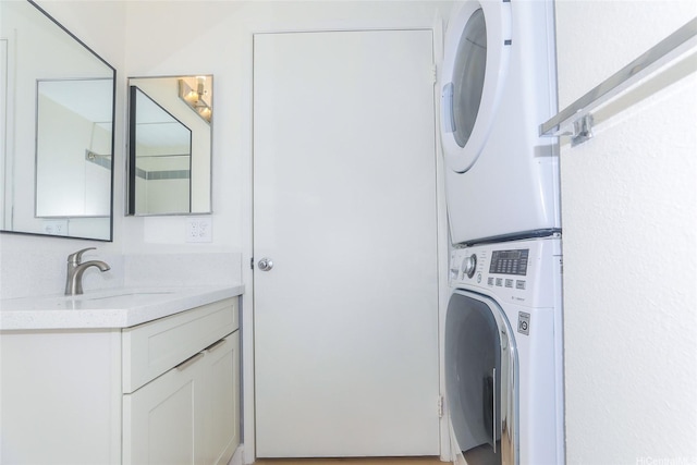laundry room featuring stacked washer / drying machine, a sink, and laundry area