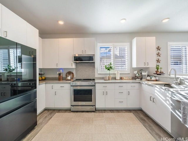 kitchen featuring light wood-style flooring, appliances with stainless steel finishes, light countertops, and a sink