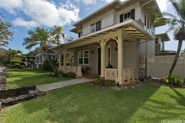 view of front of property featuring covered porch, fence, and a front yard