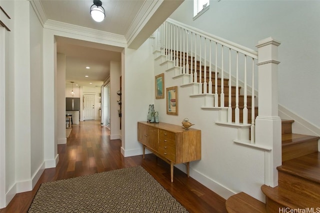 staircase with ornamental molding, baseboards, and wood finished floors