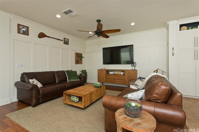 living room with crown molding, visible vents, and a decorative wall