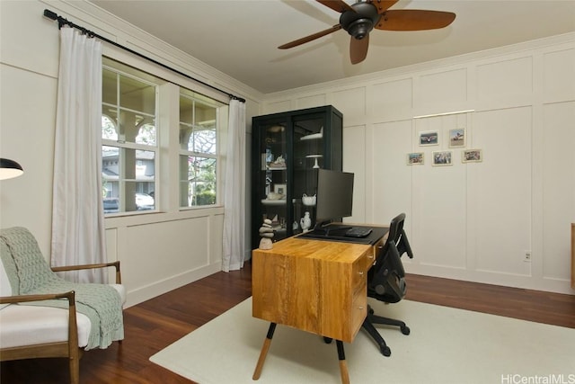 office area with dark wood-style floors, a ceiling fan, a decorative wall, and ornamental molding