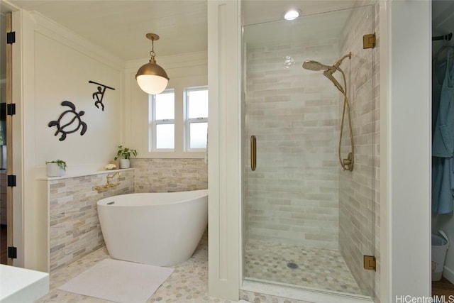 bathroom featuring ornamental molding, tile walls, a freestanding tub, and a shower stall