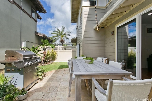 view of patio with outdoor dining space, fence, and area for grilling