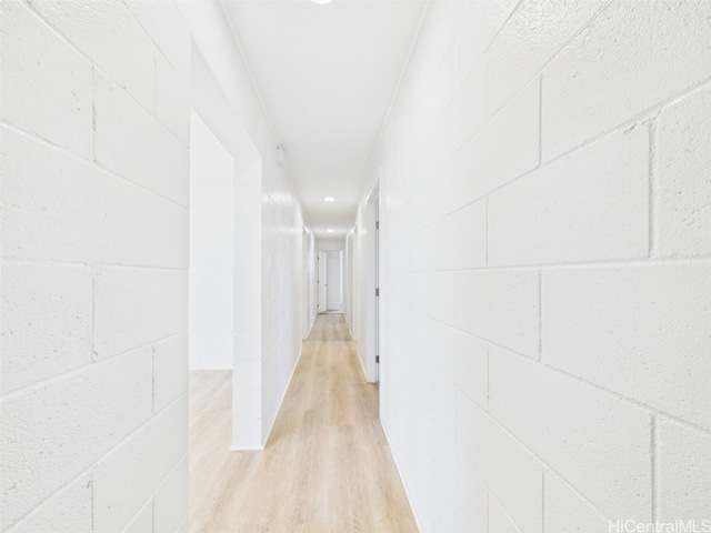 hallway with concrete block wall and light wood-style flooring