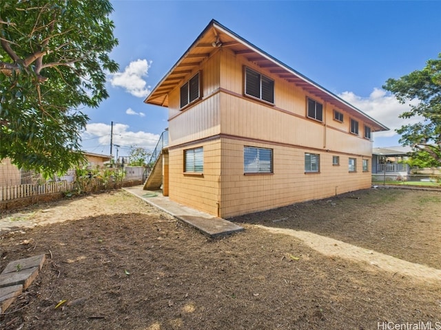 view of home's exterior with stairs and fence