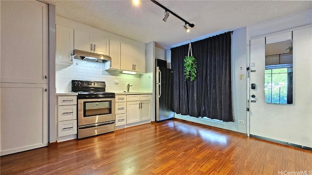 kitchen with white cabinets, appliances with stainless steel finishes, light countertops, light wood-type flooring, and under cabinet range hood