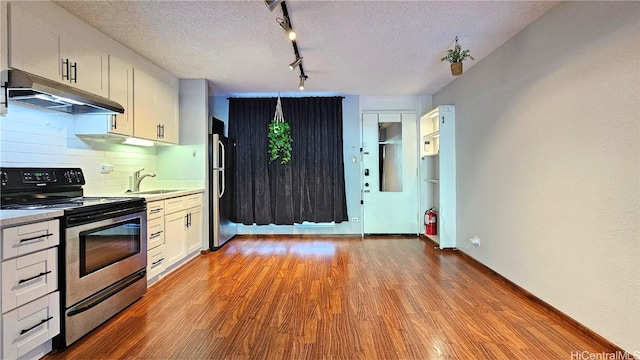 kitchen with under cabinet range hood, a sink, white cabinets, light countertops, and appliances with stainless steel finishes