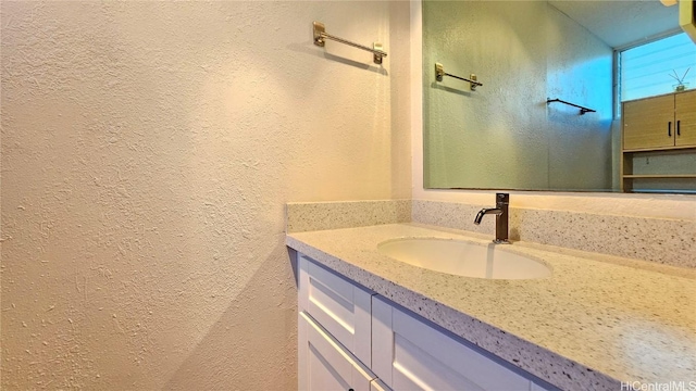 bathroom with a textured wall and vanity