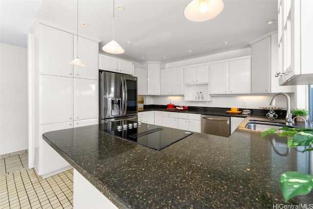 kitchen featuring a peninsula, a sink, white cabinets, appliances with stainless steel finishes, and pendant lighting