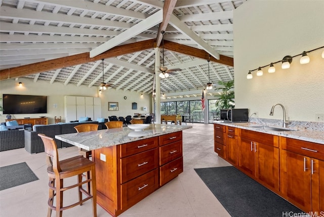 kitchen featuring light stone counters, open floor plan, a sink, and black microwave