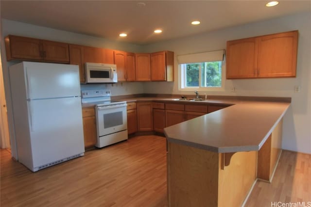 kitchen featuring white appliances, light wood-style flooring, a peninsula, a sink, and recessed lighting