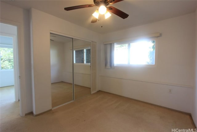 unfurnished bedroom featuring ceiling fan, a closet, and light colored carpet