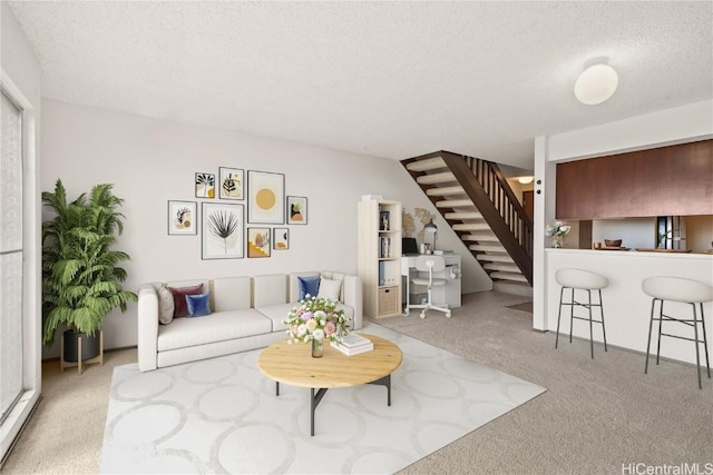 carpeted living area featuring a textured ceiling and stairs