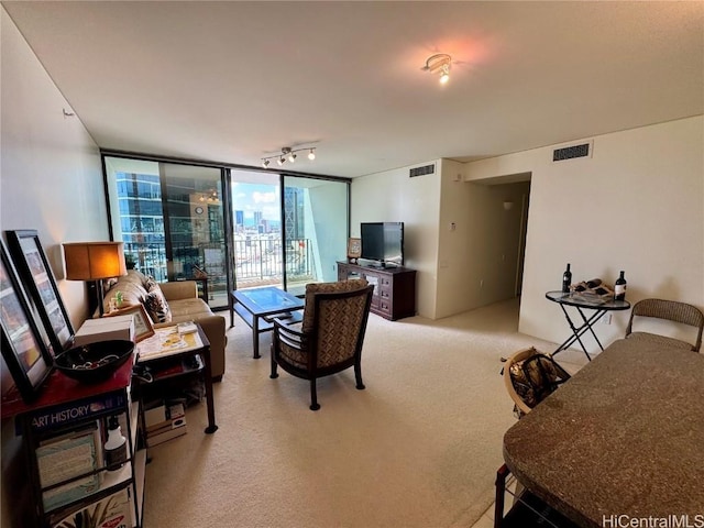 living room featuring rail lighting, floor to ceiling windows, visible vents, and light colored carpet