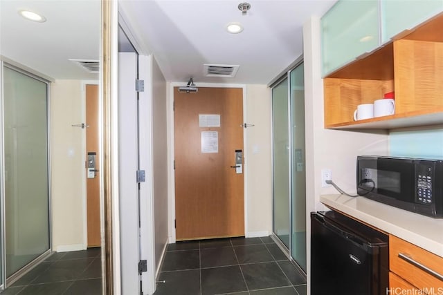 kitchen with black microwave, light countertops, dark tile patterned floors, and open shelves