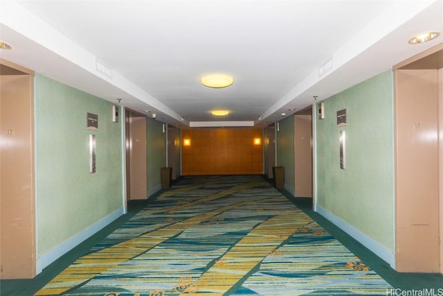 hallway featuring baseboards and dark colored carpet