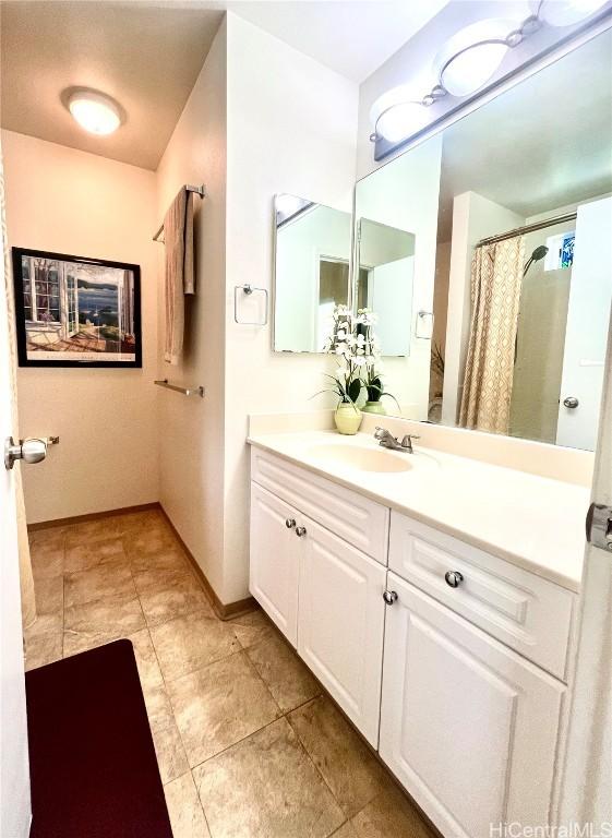 full bathroom with a shower with shower curtain, baseboards, and vanity