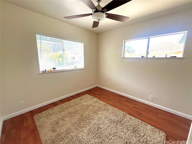 unfurnished room with wood finished floors, a ceiling fan, and baseboards