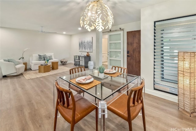 dining space with recessed lighting, wood finished floors, baseboards, and a barn door