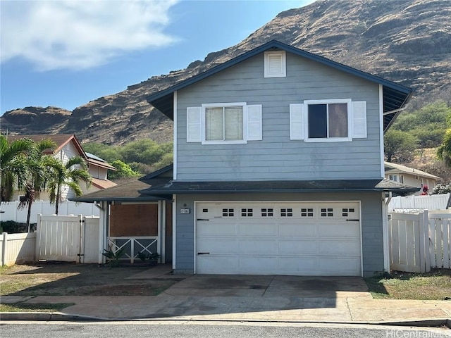 traditional home with a garage, driveway, fence, and a mountain view