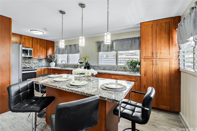 kitchen with light stone countertops, appliances with stainless steel finishes, a breakfast bar area, and a center island