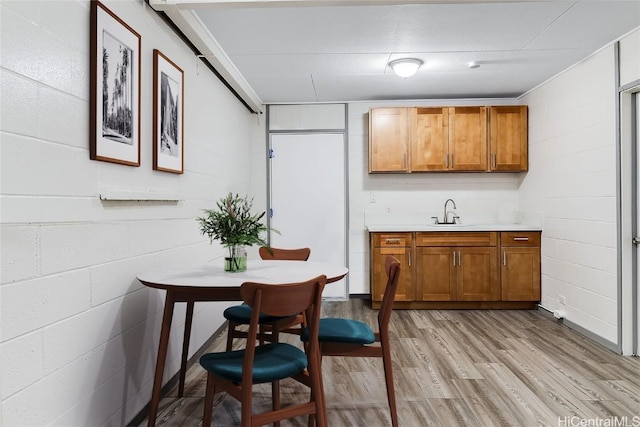 interior space with concrete block wall, a sink, and light wood finished floors