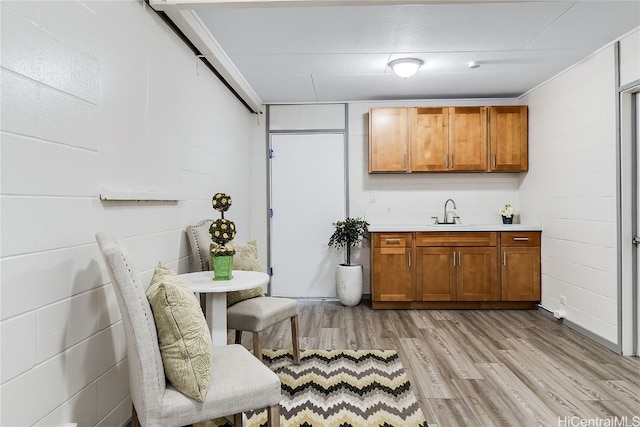 bar featuring a sink, light wood-style flooring, and concrete block wall