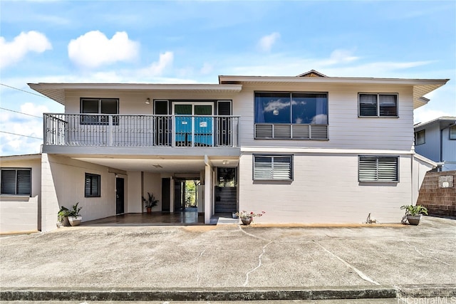 view of front of house with a carport, driveway, and a balcony