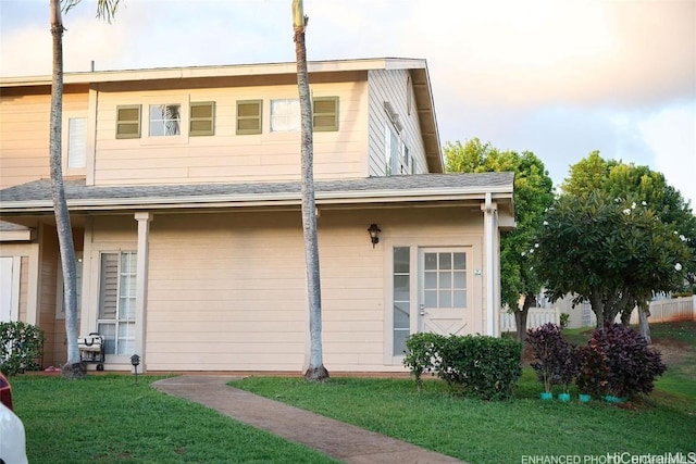 back of property featuring roof with shingles and a lawn