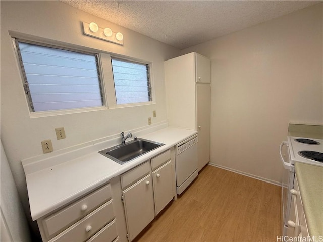 kitchen featuring white appliances, light wood finished floors, white cabinets, light countertops, and a sink