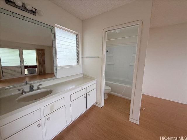 bathroom featuring a textured ceiling, toilet, wood finished floors, vanity, and washtub / shower combination