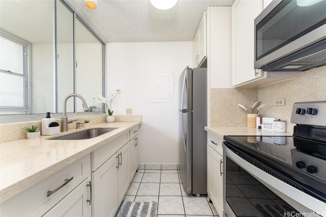 kitchen featuring white cabinets, stainless steel appliances, a textured ceiling, light countertops, and a sink