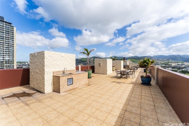 view of patio featuring a mountain view, an outdoor kitchen, a sink, and outdoor dining space