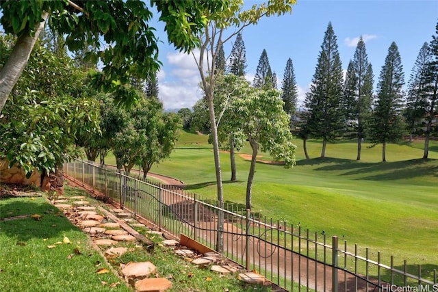 view of community featuring a yard, golf course view, and fence