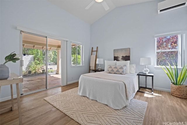 bedroom featuring light wood finished floors, access to outside, multiple windows, and a wall mounted air conditioner