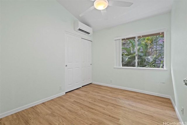 unfurnished bedroom featuring a wall mounted air conditioner, light wood-style flooring, and baseboards