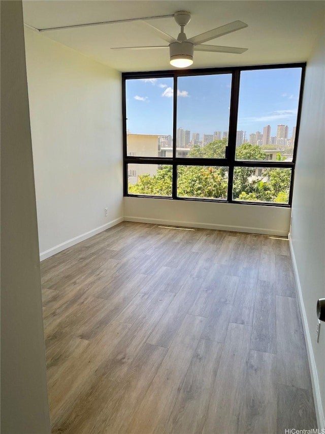 3138 Waialae Ave Unit 418, Honolulu, HI 96816 - spare room featuring a view of city, baseboards, wood finished floors, and a ceiling fan