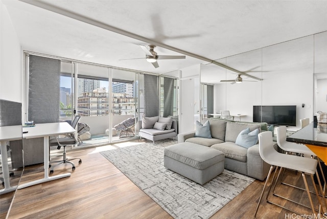 living room featuring a ceiling fan, expansive windows, and wood finished floors