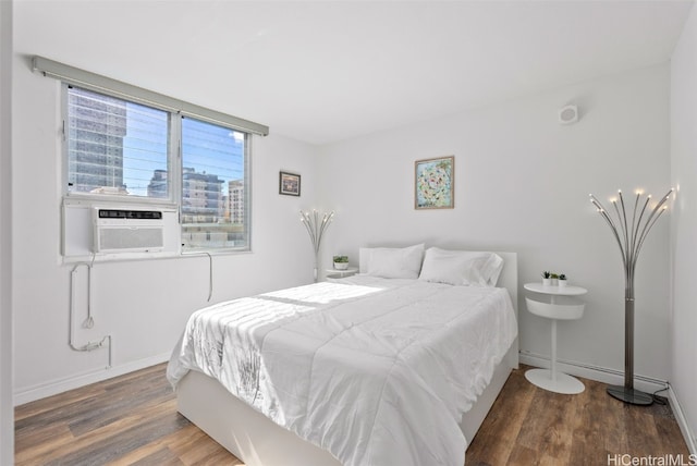 bedroom featuring a view of city, cooling unit, dark wood finished floors, and baseboards