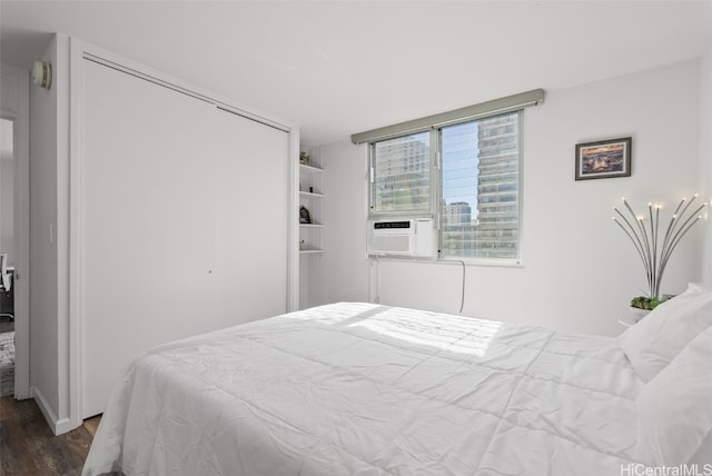 bedroom with cooling unit, dark wood finished floors, and a closet