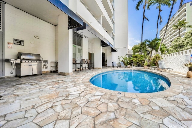 view of swimming pool with a patio, area for grilling, fence, and a fenced in pool