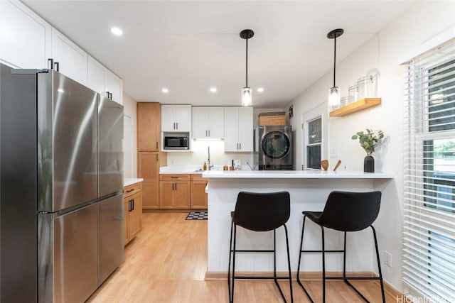 kitchen featuring a peninsula, a breakfast bar, white cabinets, light countertops, and appliances with stainless steel finishes