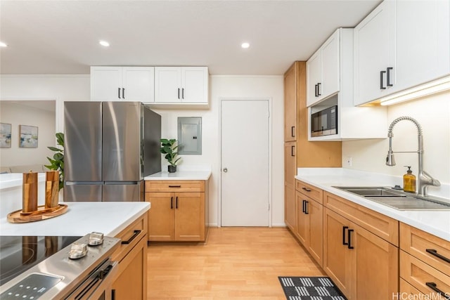 kitchen featuring freestanding refrigerator, built in microwave, light countertops, light wood-type flooring, and a sink