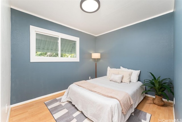 bedroom featuring crown molding, wood finished floors, and baseboards